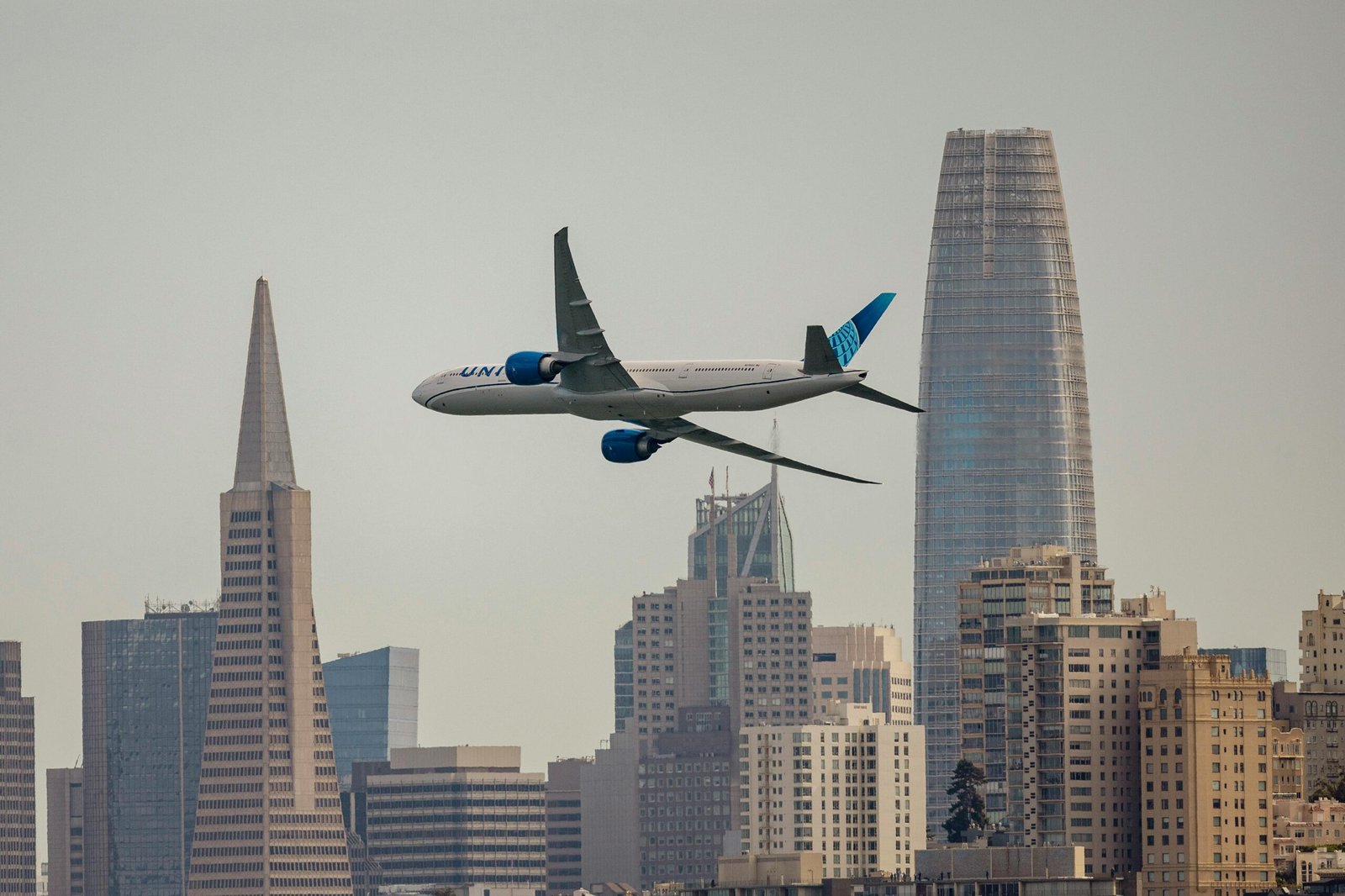 A United Airlines jet soaring over the iconic San Francisco skyline.